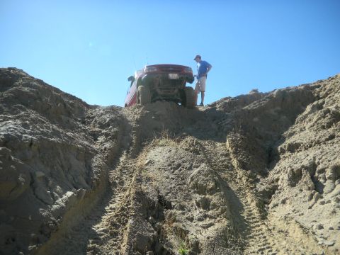 1997 Ford Ranger - A red pickup truck is positioned at the crest of a steep, sandy incline under a clear blue sky.
