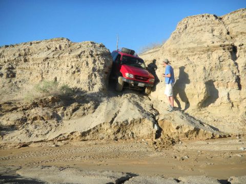 1997 Ford Ranger - A man watches a red SUV attempt to drive through a narrow, challenging off-road path.
