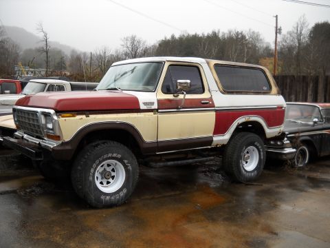 1982 Ford Bronco - This two-tone Ford Bronco is parked next to another vehicle in an outdoor lot.
