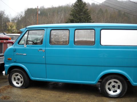 1982 Ford Bronco - A blue van with a flat front tire is parked next to a red truck.