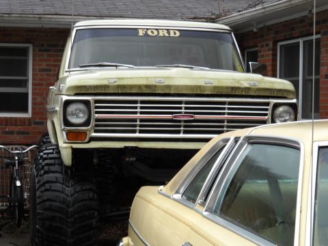 1982 Ford Bronco - This lifted Ford truck features a prominent "FORD" banner on the windshield and massive off-road tires.