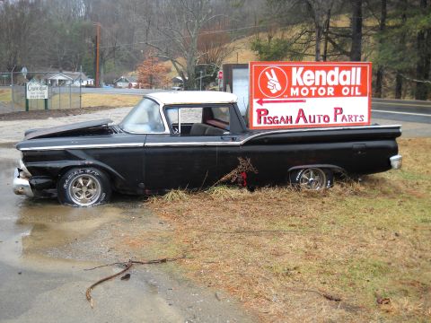 1982 Ford Bronco - A vintage Ford Ranchero sits abandoned with its hood open, adorned by a vintage auto parts sign.
