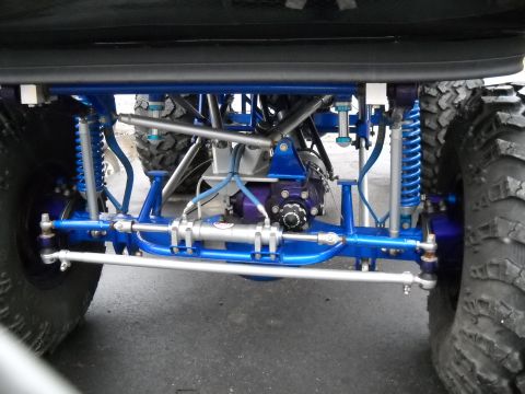1982 Ford Bronco - Custom front axle and suspension system with bright blue components and oversized tires, likely for off-road use.