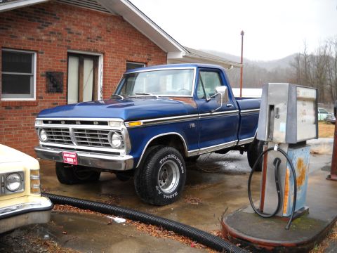 1982 Ford Bronco - Blue Ford F-Series pickup truck from the early 1970s parked at a gas station.