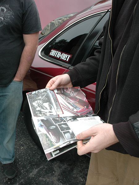 1992 Ford Crown Victoria - Brochure displays various car images, held near a red vehicle with a sticker on the window.