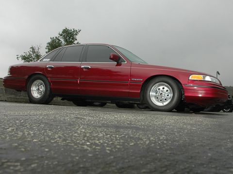 1992 Ford Crown Victoria - Side view of a red 1992 Ford Crown Victoria with aftermarket wheels.