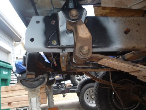 1979 Ford Bronco - Underbody view of a freshly painted black boxed frame rail with a bare-steel bracket welded and bolted on with yellow-zinc hardware, and a…