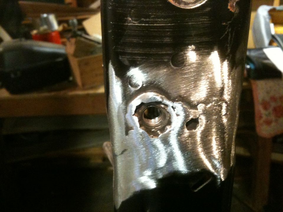 Metal bracket with a damaged threaded hole and surrounding metalwork