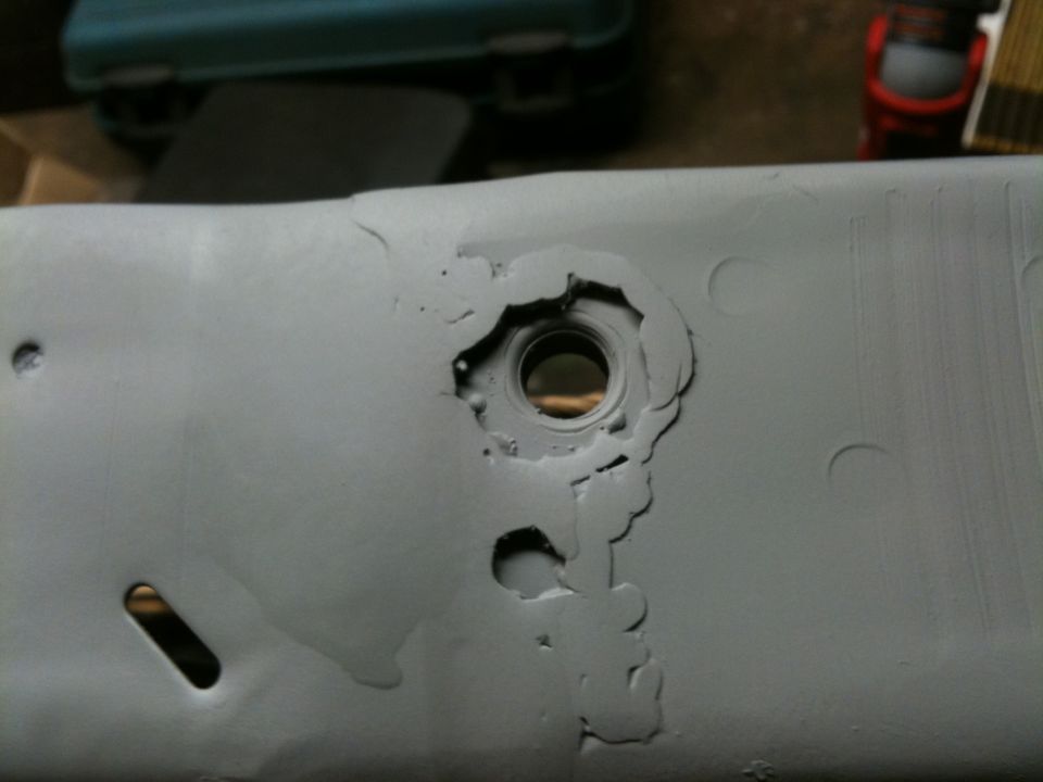 Rusted metal part with a circular hole and surrounding damage