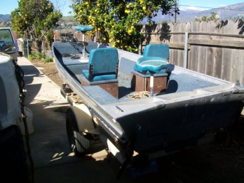 1968 Ford Mustang - A fishing boat with two rows of seats is parked on a trailer in a yard.