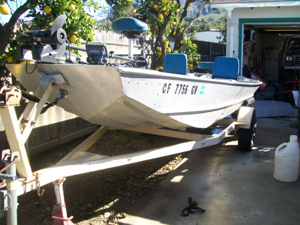 Boat with registration CF 7756 GV on a trailer under a lemon tree