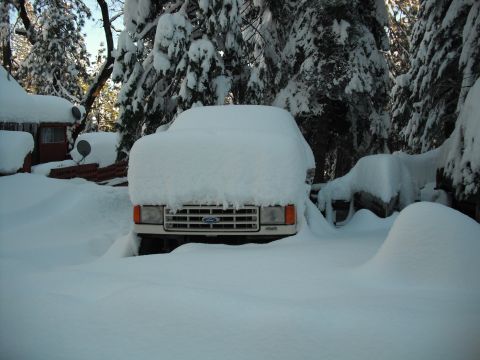 1991 Ford Bronco - A 1991 Ford Bronco is completely covered in snow, with only the grille visible, during a winter storm.