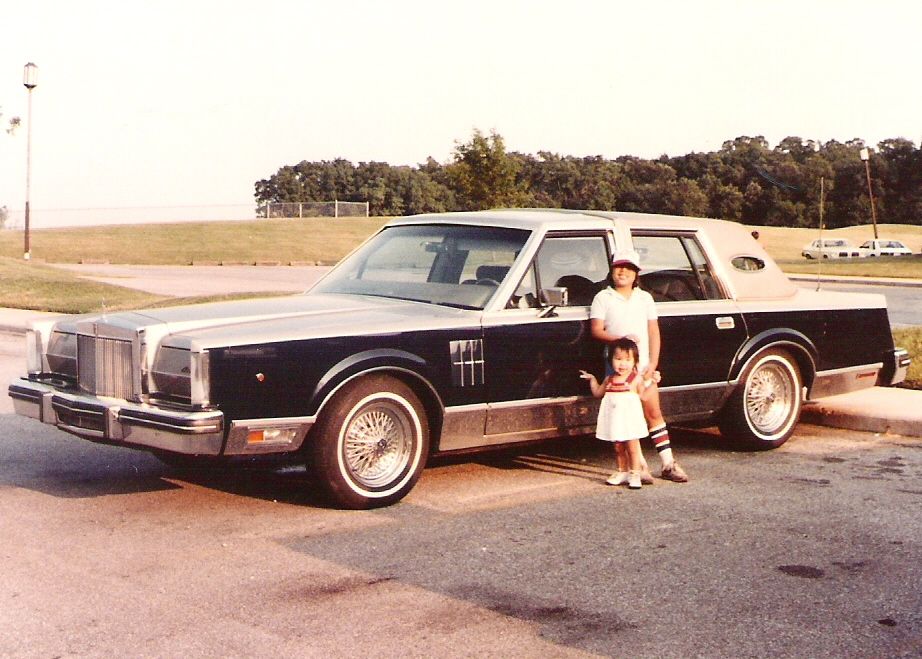 Black and silver Lincoln Town Car with wire wheels, parked on asphalt