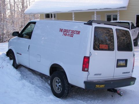 1990 Chevrolet Suburban - A white cargo van is stuck in the snow, with a pickup truck in the background.