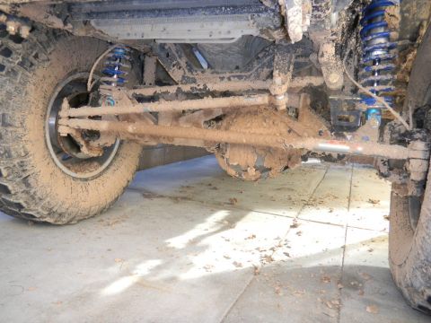 1997 Ford Ranger - Undercarriage of a vehicle heavily coated in mud, showing suspension and drivetrain parts.
