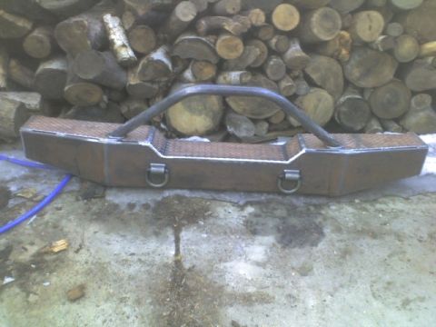 1989 Ford Bronco - A custom-fabricated steel bumper with integrated brush guard and D-ring mounts is shown in front of a pile of firewood.