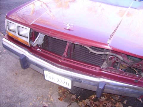 1988 Ford Crown Victoria LTD - The front end of a maroon car shows significant damage, with the grille and radiator exposed.