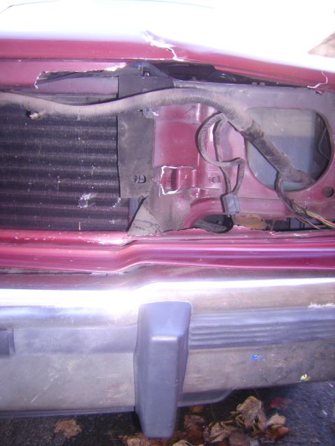 1988 Ford Crown Victoria LTD - Damage to the front end of a red vehicle, revealing the radiator and bumper structure.