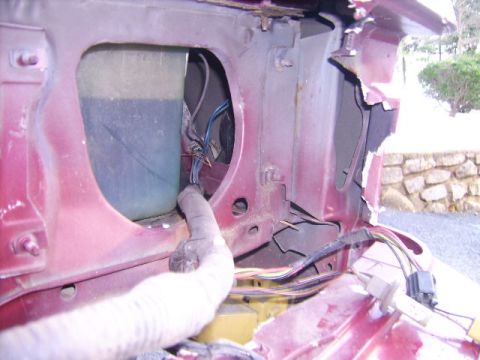 1988 Ford Crown Victoria LTD - Damage to a car's fender reveals exposed wiring and a fluid reservoir.