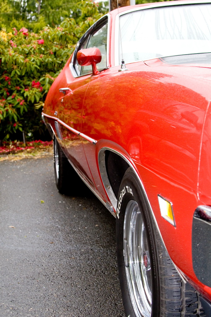 Low side view of red 1970s Ford coupe fender with Radial T/A tire and polished wheel