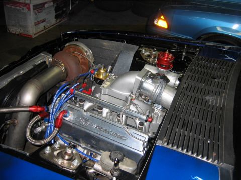 1992 Ford Mustang - The engine bay of a blue 1992 Ford Mustang is visible, a large turbocharger and custom modifications.