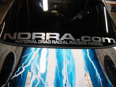 1992 Ford Mustang - The rear window of a vehicle features a large NDRRA.COM sticker and custom lightning bolt graphics.
