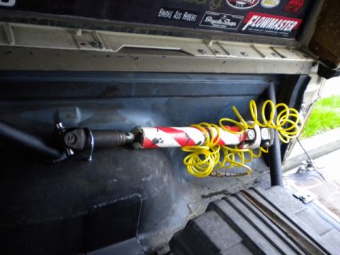 1989 Ford Bronco - A close-up view of a modified driveshaft with a yellow coiled hose, inside a vehicle's interior.