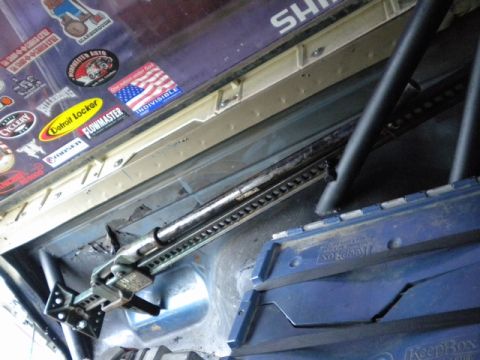 1989 Ford Bronco - A hi-lift jack is mounted inside a vehicle, surrounded by various stickers on the interior ceiling.