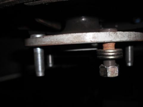 1991 Ford Bronco - This image shows a close-up view of a bolt, washers, and nut securing a metal plate, likely a component of a vehicle's suspension system.