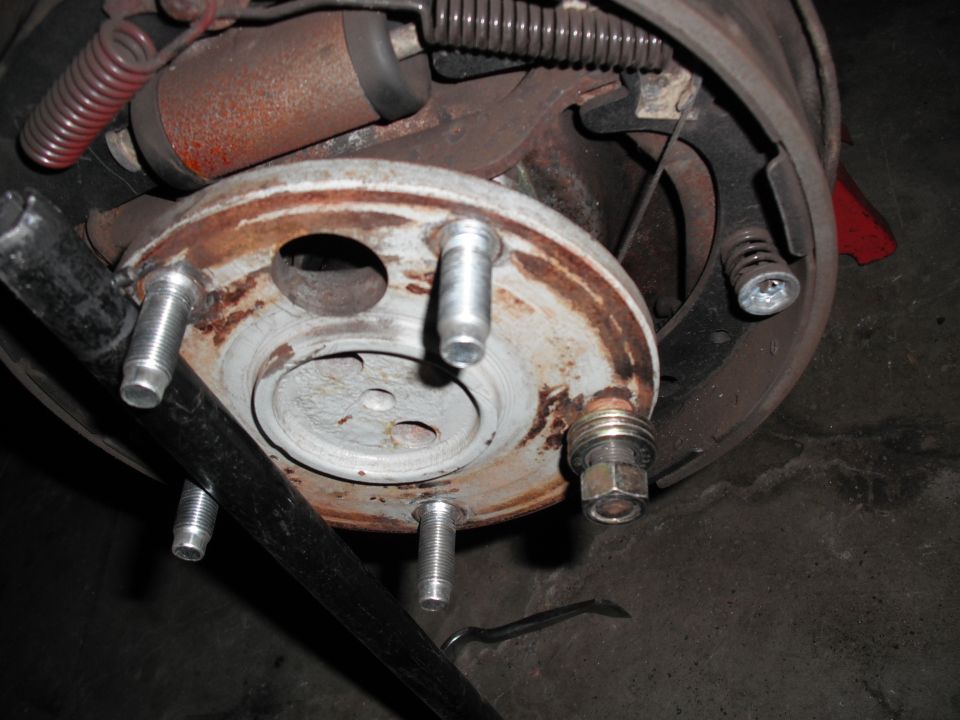Rear axle flange with white-painted hub and wheel studs, drum removed to expose brake shoes
