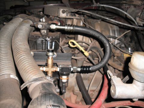 1991 Ford Bronco - Close-up view of engine components including hoses, filters, and a yellow dipstick.