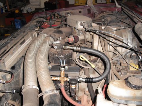 1991 Ford Bronco - Engine bay with modifications, including large intake hoses and fuel lines. Year is not discernible.