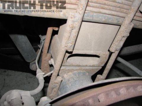 1979 Ford Bronco - Close-up view of a vehicle's rear suspension system, showing leaf springs and a shock absorber.