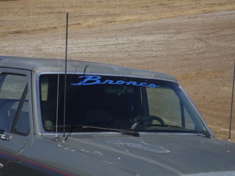 1989 Ford Bronco - A gray Ford Bronco is shown from the front with a blue decal on the windshield.