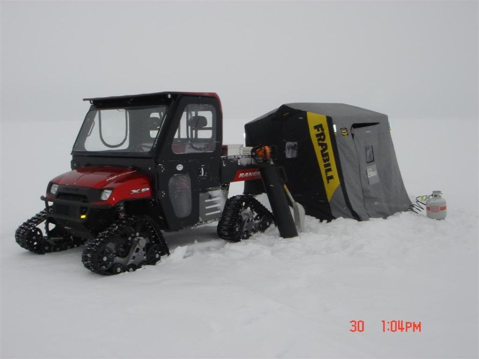 Red Polaris Ranger UTV on tracks pulling a Frabill ice shelter on snow