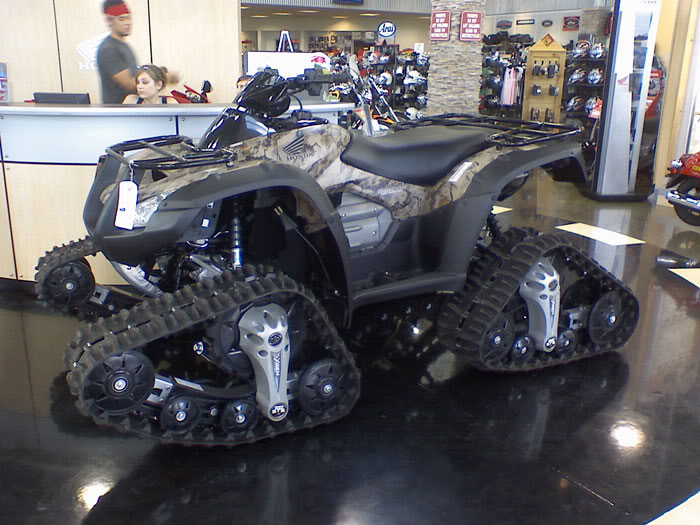 Camo Honda ATV on rubber track conversion inside a dealership showroom