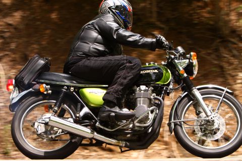 1985 Ford Crown Victoria LTD - A rider on a green and black Honda motorcycle cruises down a wooded road, displaying the classic bike's engine and exhaust system.