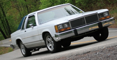 1985 Ford Crown Victoria LTD - White 1985 Ford Crown Victoria LTD two-door sedan driving on a country road.