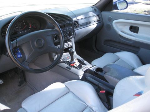 1994 Ford Probe - The interior of a BMW shows light grey leather seats and a dashboard with a manual transmission shifter.