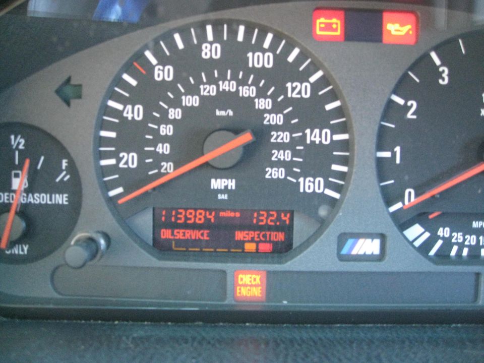 Car dashboard with speedometer, fuel gauge, and warning lights for oil service, inspection, and check engine