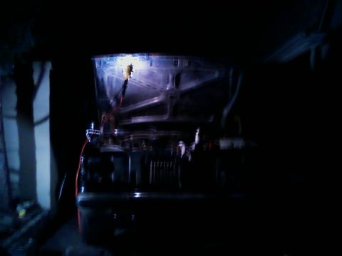 1990 Ford Bronco - The engine bay of a vehicle is illuminated, revealing various mechanical parts and electrical wiring.