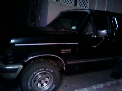 1990 Ford Bronco - A black Ford Bronco is seen from the side, parked in what appears to be a driveway at night.