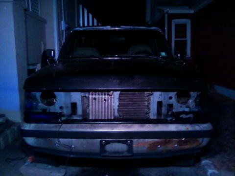 1990 Ford Bronco - Front view of a black Ford Bronco with its grille and headlights removed, revealing the radiator and front frame.