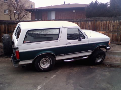 1996 Ford Bronco - This two-tone Ford Bronco features a lifted suspension and off-road tires, with a spare tire mounted externally on the rear.