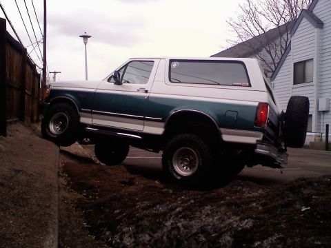 1996 Ford Bronco - This two-tone Ford Bronco is shown from the side, with its front wheels on a dirt embankment.