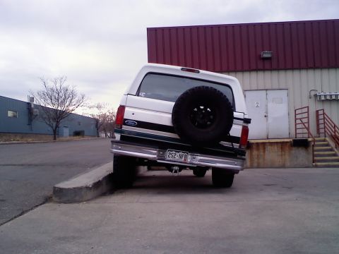 1996 Ford Bronco - 1996 Ford Bronco parked with its rear wheels on a concrete curb.