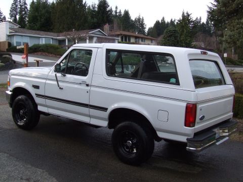 1996 Ford Bronco - This white 1996 Ford Bronco is shown from a rear three-quarter view on a wet street.