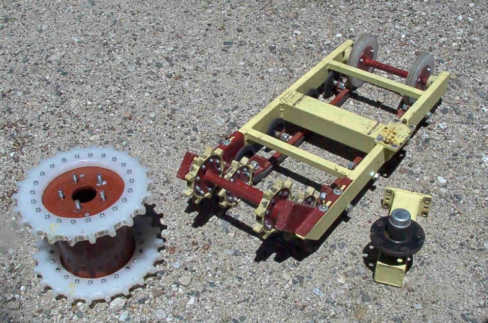 Yellow metal roller frame, white sprocket drum, and black hub part on concrete
