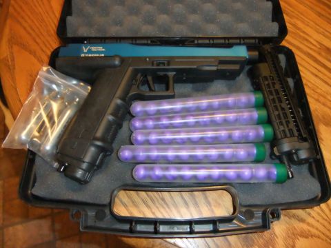 1978 Chevrolet C/K Pickup - A paintball gun kit with accessories is displayed in its case on a wooden surface.