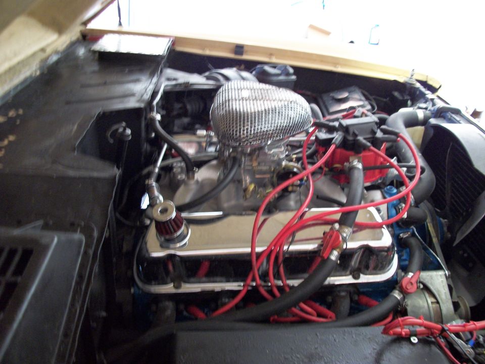 V8 engine with chrome air cleaner, chrome valve covers, and red plug wires in a Bronco engine bay